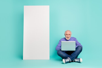 Poster - Full body portrait of positive man sit floor use netbook empty space huge screen isolated on aquamarine color background