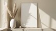 A white framed picture sits on a shelf next to a vase of dried grass