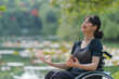 © Kanurism - Disabled Asian woman sitting in wheelchair meditating health yoga outdoors