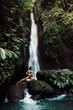 Fashionable woman in bikini posing on waterfall. Traveler young girl