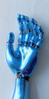 Mano artificial robótica, azul y gris, mecanismo para implante, sustitución o reemplazo de una extremidad. Ayuda especializada fondo azul gris claro, sentido vertical visto de frente
