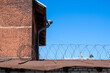 Roof of a building with barbed wire against a blue sky