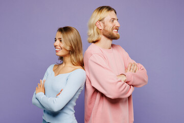 Wall Mural - Sideways young couple two friends family man woman wear pink blue casual clothes together stand back to back hold hands crossed folded isolated on pastel plain light purple background studio portrait.
