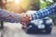 © furyon - customer and insurance agent handshake agreeing on car insurance terms blurred vehicle background