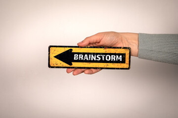 Wall Mural - Brainstorm. Arrow with text in woman's hand on white background