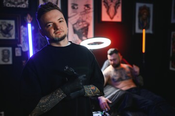 Wall Mural - tattoo artist demonstrates the process of getting black tattoo with paint. Master works in black sterile gloves