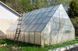 Greenhouse on next to cottage with attached wooden ladder.