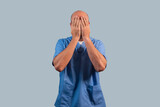 Fototapeta  - Portrait of a female physiotherapist wearing light blue dress and hands covering her face.