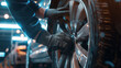 Hands of a mechanic expertly servicing a car's alloy wheel in a well-equipped workshop.