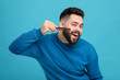 Handsome young man combing beard on light blue background