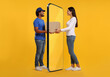 © New Africa - Courier delivering parcel to woman through huge smartphone on orange background