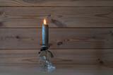 Fototapeta Natura - Silver color candle is burning in the glass and metal candlestick holder on wooden wall background.