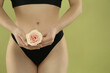 Gynecology. Woman in underwear with rose flower on green background, closeup. Space for text