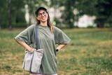 Fototapeta Niebo - Young woman with glasses holding empty cotton eco bag, mockup design. High quality photo