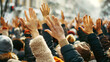 Numerous raised hands amidst a crowd at an outdoor event, with a soft-focus winter background.