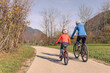 Two cyclists, a mother with a girl child on a bike ride along the road in rural nature. Family recreation concept.