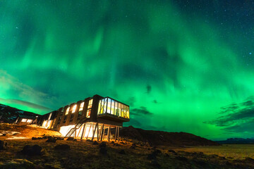 Wall Mural - aurora borealis, northern lights glowing over luxury hotel on volcanic wilderness in winter at icela