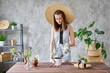 Portrait of Woman gardener transplanting plants. Concept of home garden. Flower and garden shop. A straw hat with a wide brim.