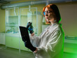 Woman chemist. Laboratory technician with electronic tablet. Test tube in hands of woman chemist. Employee is standing in industrial laboratory. Girl student studying to become chemist