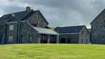 Canvas Print - Scenic view of Irish homes on green meadow under cloudy sky