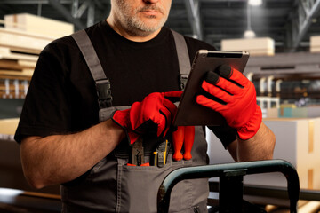 Poster - Warehouse manager. Storekeeper with electronic tablet. Cropped warehouse manager. Man with gadget near conveyor belt. Storekeeper is holding tablet computer. Concept using digital tech in warehouse