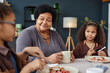 Portrait of senior African American woman with two girls enjoying breakfast together at kitchen table