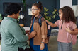 Side view portrait of Black senior woman helping girl with backpack getting ready for school