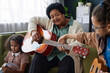 Portrait of African American senior woman playing guitar at home with two little girls