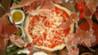 Super slow motion of falling pieces of ham on pizza dough with sugo, top down view