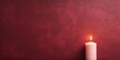Maroon background with white thin wax candle with a small lit flame for funeral grief death dead sad emotion with copy space texture for display 