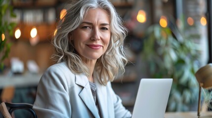 Wall Mural - A smiling middle-aged businesswoman sits confidently at the table. The laptop is open in front of you. This is a testament to the power of technology. Bringing people together to achieve shared goals