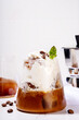 Latte coffee summer cocktail. Cold brewed iced cappuccino coffee,  with whipped foamy cream or non-dairy milk and frozen coffee ice cubes, on white kitchen background copy space