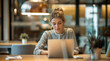 © Vladimir - A young woman works on a laptop while sitting at a table in a modern bright office