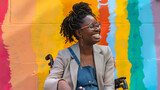 Fototapeta Dmuchawce - Happy african American businesswoman in wheelchair smiling against rainbow pride mural. Black history month. Successful ambitious black woman with disability. Inclusion  AI