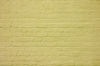The brick wall is painted with yellow paint. Abstract construction background.