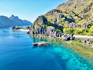 Canvas Print - Aerial view of a boat near a green tropical landscape on a sunny day