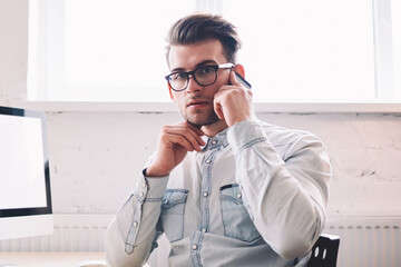 Poster - Confident male programmer talking with operator for checking account balance looking at camera while sitting indoors with computer with blank screen for your internet advertising on background