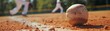 © Cheetose - Little league baseball game with a close up of the ball on the infield dirt with blurred players in the background.