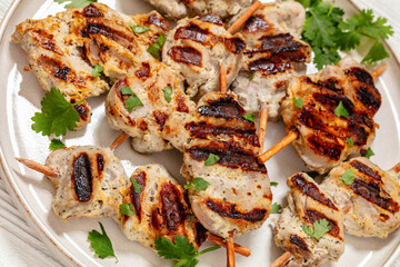 Wall Mural - grilled mini pork skewers on a plate, top view