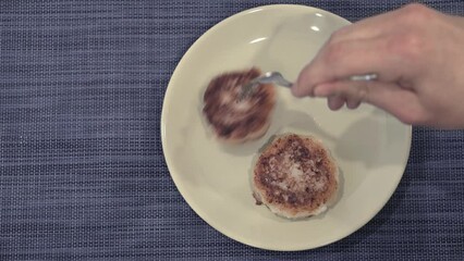 Wall Mural - A man puts cottage cheese pancakes with a fork on a plate. Close-up. Copy space.