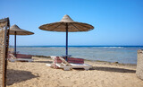 Fototapeta Mosty linowy / wiszący - Beautiful sandy beach with sun loungers and umbrellas, Marsa Alam region, Egypt.