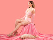 A young beautiful brunette girl in a sexy pink dress on a pink background.