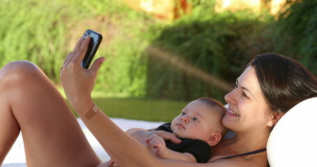 Wall Mural - Mother taking selfie with baby son outside by the poolside