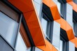 A closeup of a corporate office building with a striking geometric facade in orange color, showcasing its abstract design and numerous windows