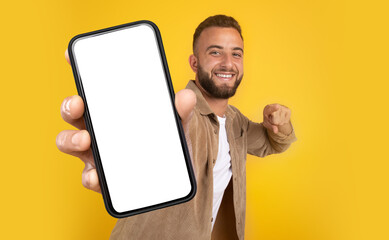 Poster - A man holds a cell phone in his hand, showing a focused expression. His hand grips the phone firmly as he looks intently at the screen, mockup copy space