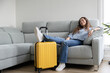 © roberto - Woman resting on the sofa with travel suitcases prepared