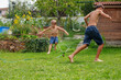 Young boys enjoy refreshing splash run around garden sprinkler