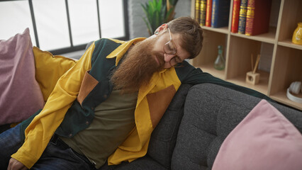 Sticker - Redhead bearded man napping on a sofa with colorful cushions in a cozy indoor setting