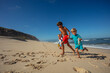 Kids race on a sandy beach in Portugal holding hands with smile