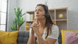 © Krakenimages.com - A thoughtful hispanic woman wearing a headset at home, reflecting while indoors.